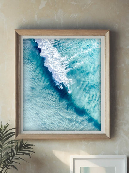 Framed aerial surf photography print displayed in a timber frame on a wall