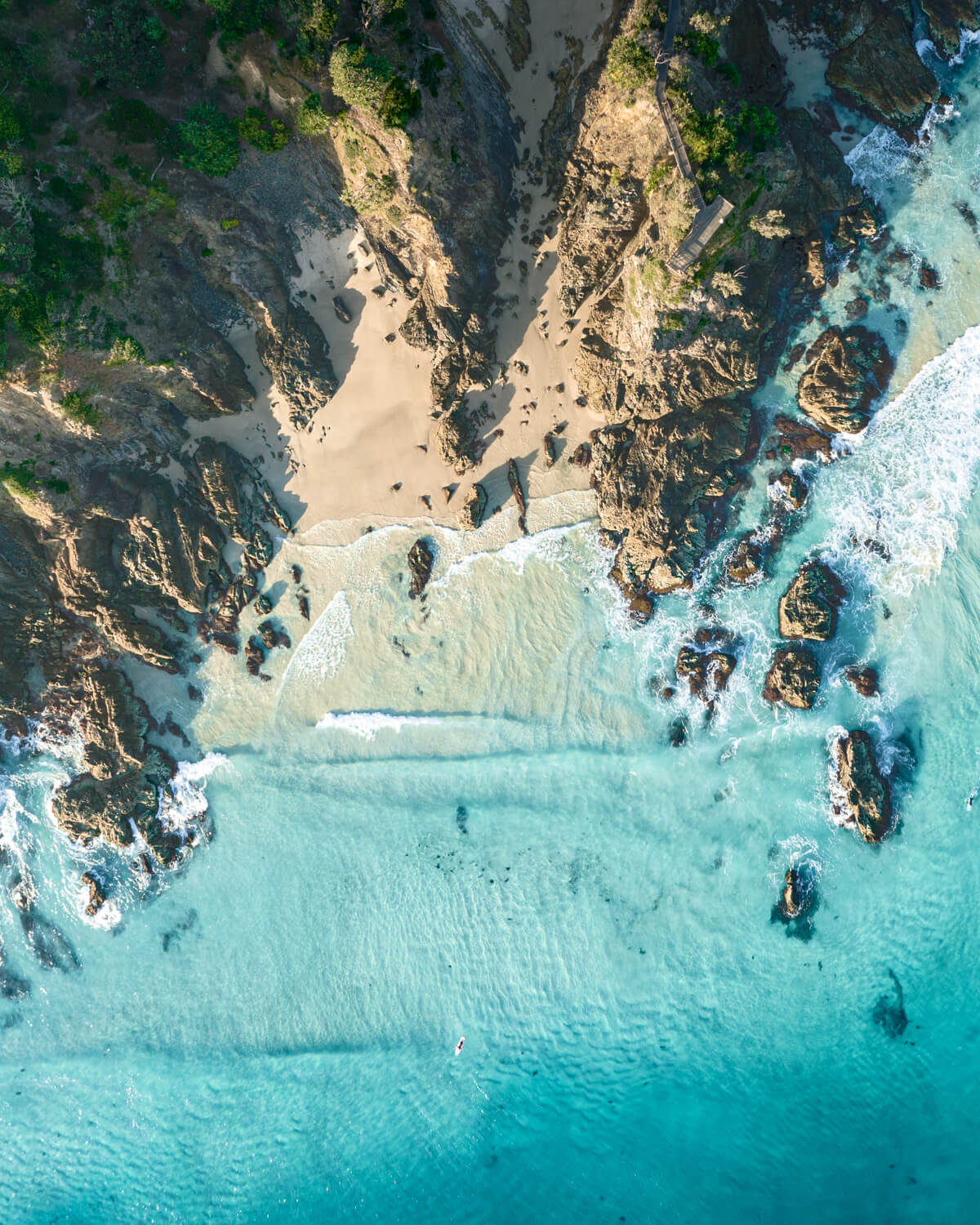 Aerial photography of The Pass headland and surfers at Byron Bay, NSW