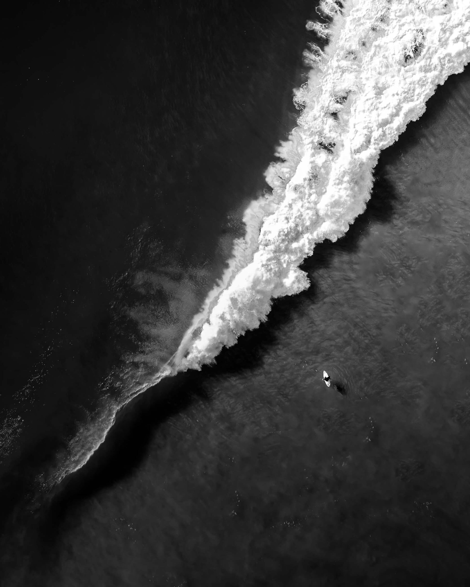 Aerial black and white photograph of a lone surfer on dark water at Bronte Beach, Sydney, by Nicolas Letoublon