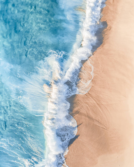 Aerial view of turquoise water and a white wave meeting the sandy shore at Bronte Beach, Sydney