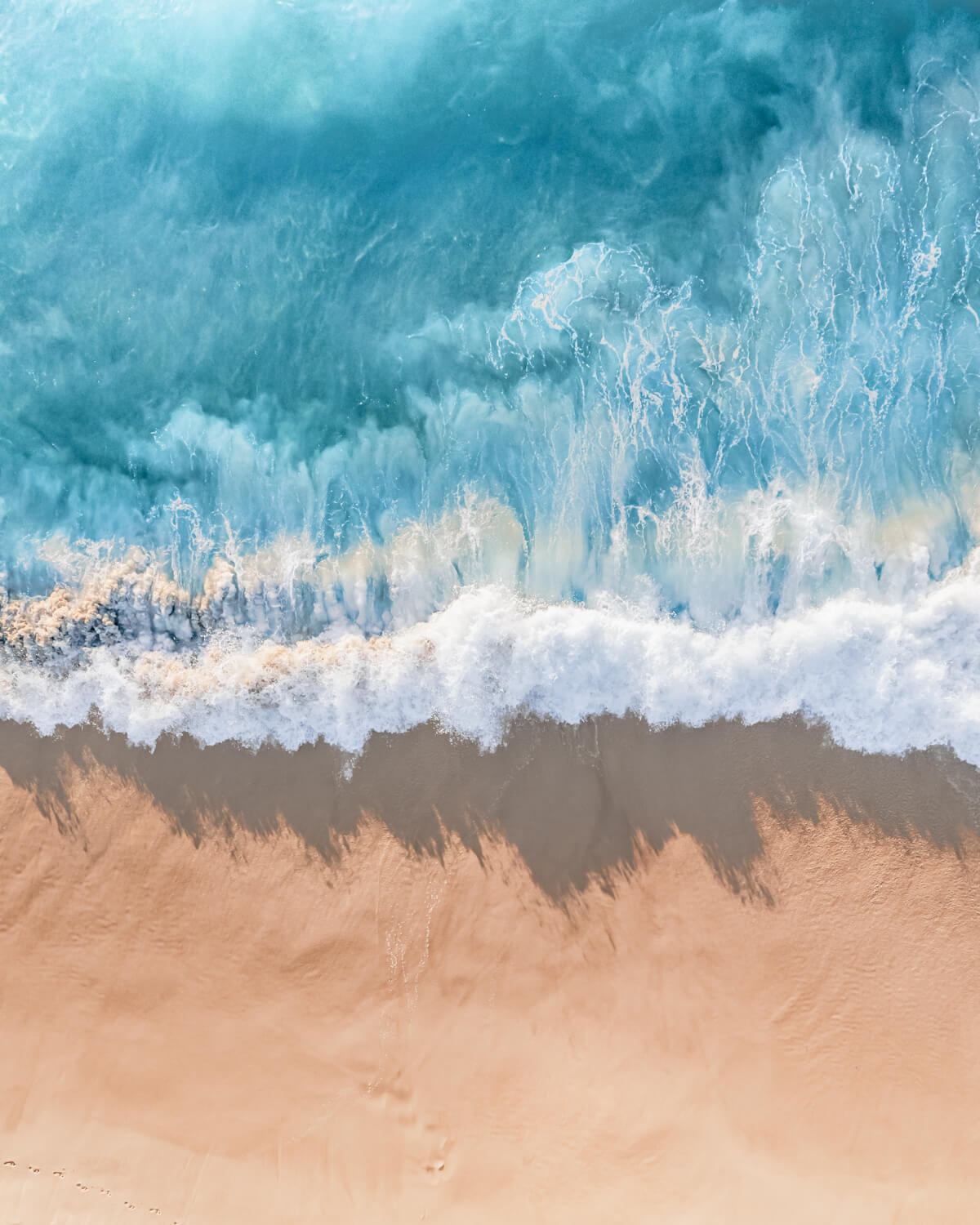 Aerial view of ocean waves meeting a sandy beach along the Australian coastline