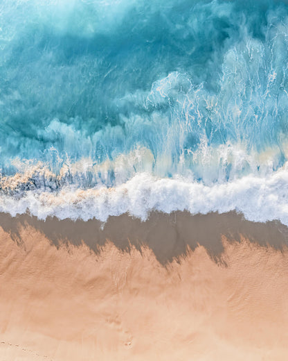 Aerial view of ocean waves meeting a sandy beach along the Australian coastline