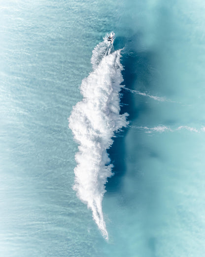 Aerial view of a lone surfer leaving a white feather-shaped wake at Bronte Beach, Sydney