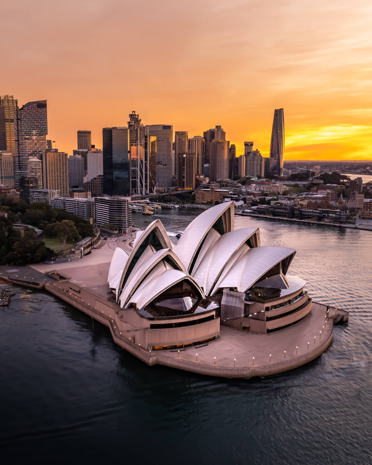 Aerial view of the Sydney Opera House at twilight with the CBD skyline glowing behind it