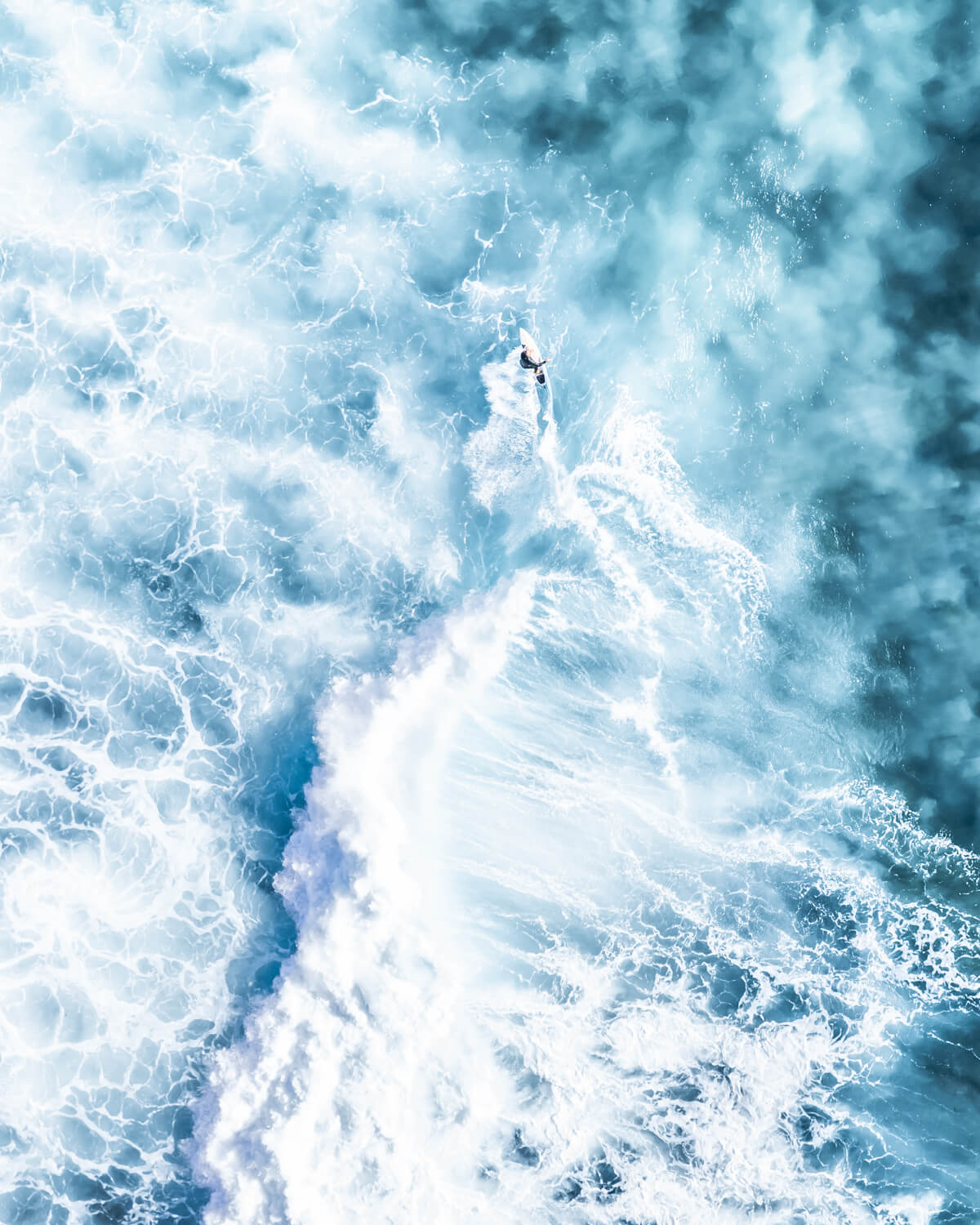 Aerial view of a surfer inside a massive white wave explosion at Bronte Beach, Sydney