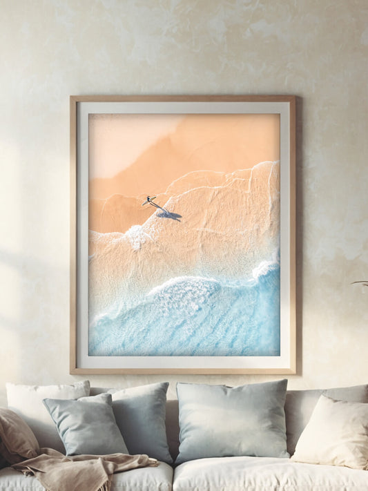 Framed aerial photography print of a lone surfer at The Pass Byron Bay on a wall