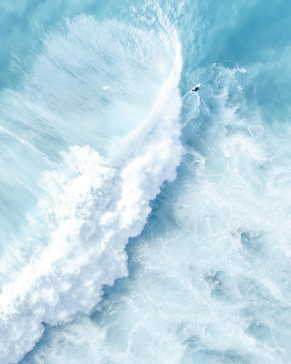 Aerial view of a surfer beneath a massive breaking wave at Bronte Beach, Sydney
