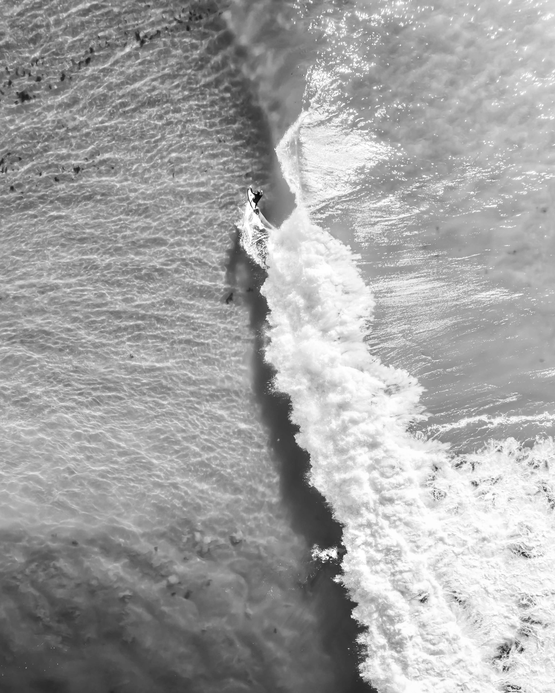 Aerial black and white photograph of a surfer carving a wave at The Pass, Byron Bay, by Nicolas Letoublon