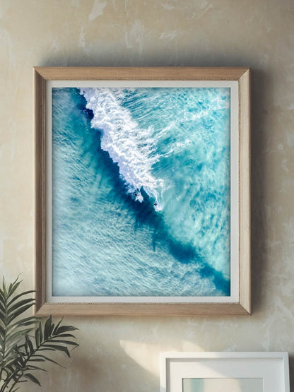 Framed aerial surf photography print displayed in a timber frame on a wall